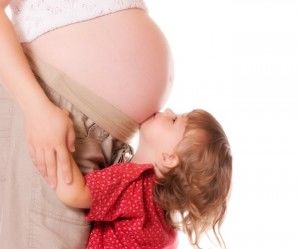 Child kissing pregnant mother